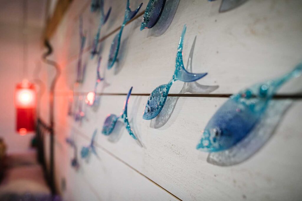 Handmade blue glass fish mounted on wooden wall cladding in a child's bedroom