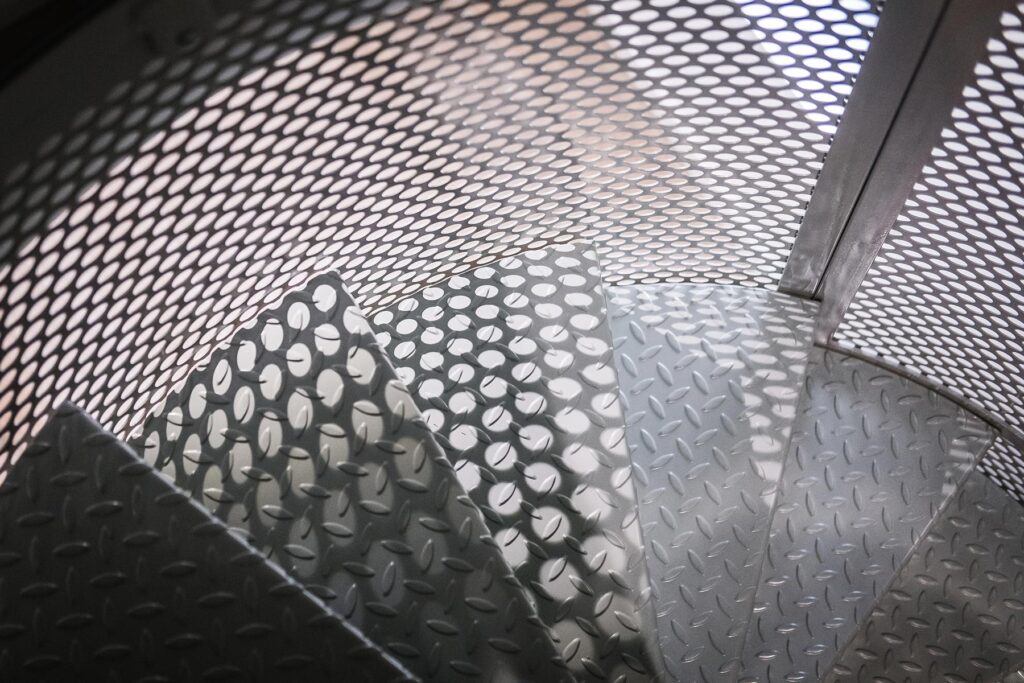 Bespoke metal spiral staircase enclosed in a spherical perforated steel design