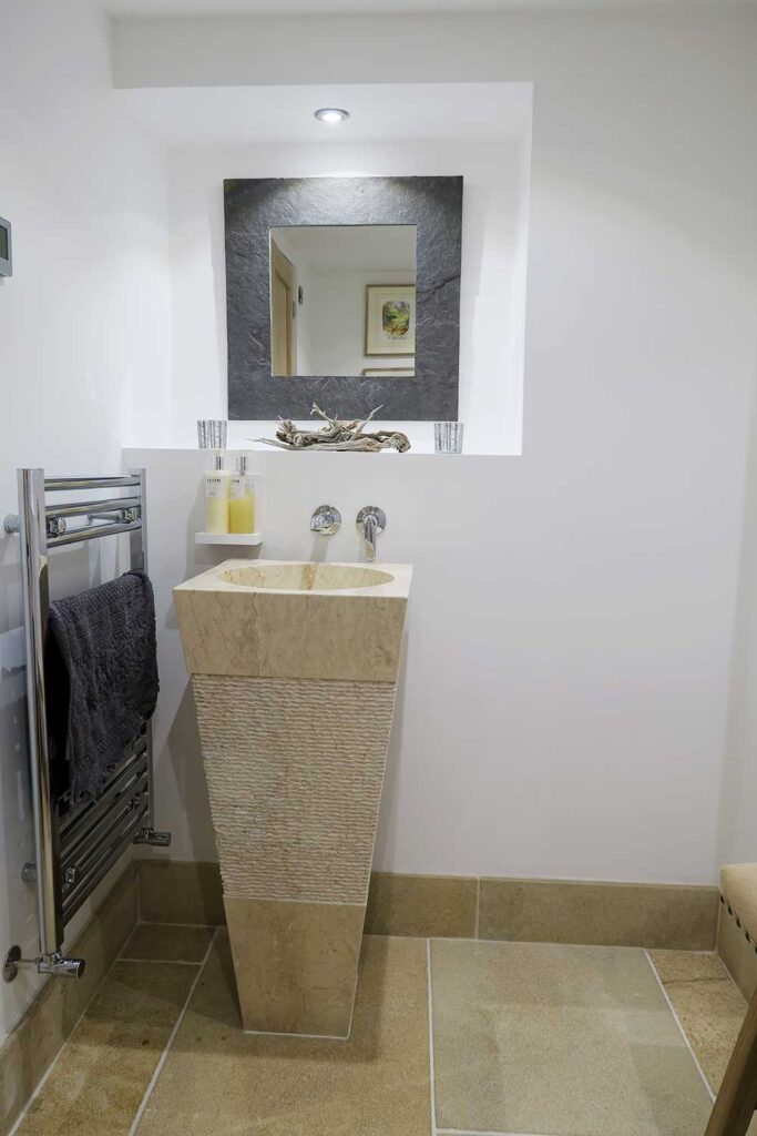 Small bathroom design with stone flooring as part of a grade II Mill Renovation project by Charlotte Findlater Design, an award winning interior design studio specialising in luxury, high-end residential & commercial projects that respect time, nature and people.