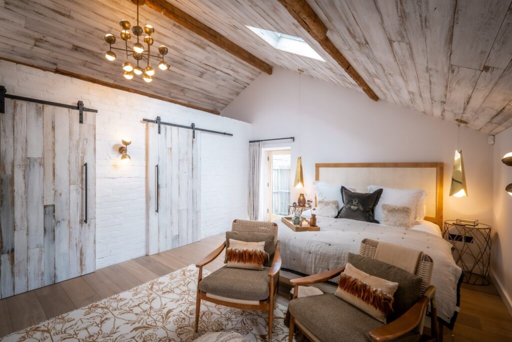Calm and serene designed bedroom suite with painted exposed stone walls, ceiling reclaimed wood cladding and wood flooring in a Scandi style designed by Charlotte Findlater Design, an award winning interior design studio specialising in luxury, high-end residential & commercial projects that respect time, nature and people.