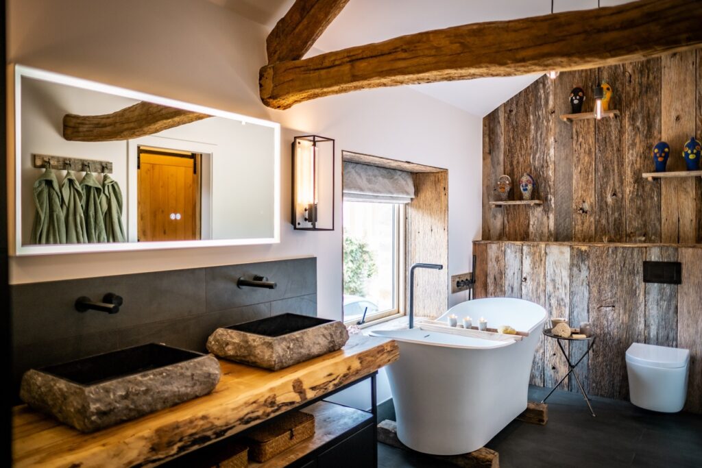 Luxury ensuite bathroom with natural stone tiling, stone basins and white slipper bath