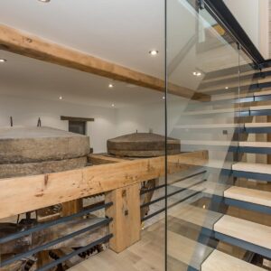 View of mill stone workings and the glass panel of a staircase inside a grade II Mill Renovation project