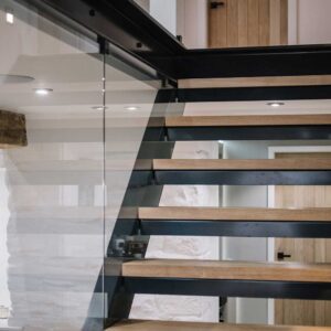 Bespoke commission of a three flights staircase with a juxtaposition of materials using a metal frame, wood treads and glass panelling. Bespoke lighting and matching metal handrail.
