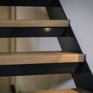 Close up of the wood treads, metal frame and accent lighting of a staircase