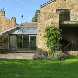 Exterior view of the bespoke lounge conservatory and garden next to the mill wheel housing as part of a grade II Mill Renovation project