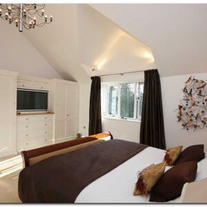 Master bedroom with double bed, bespoke cabinetry with tv and wall art