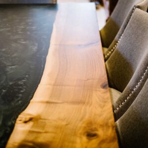 View of the right side of a bespoke dining table made from combining resin and wild walnut to create a river resin design