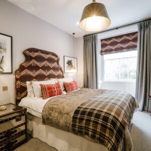 Bedroom with an earthy inspired brown, white and red immersive theme, double bed with headboard, pendant light and full height curtains