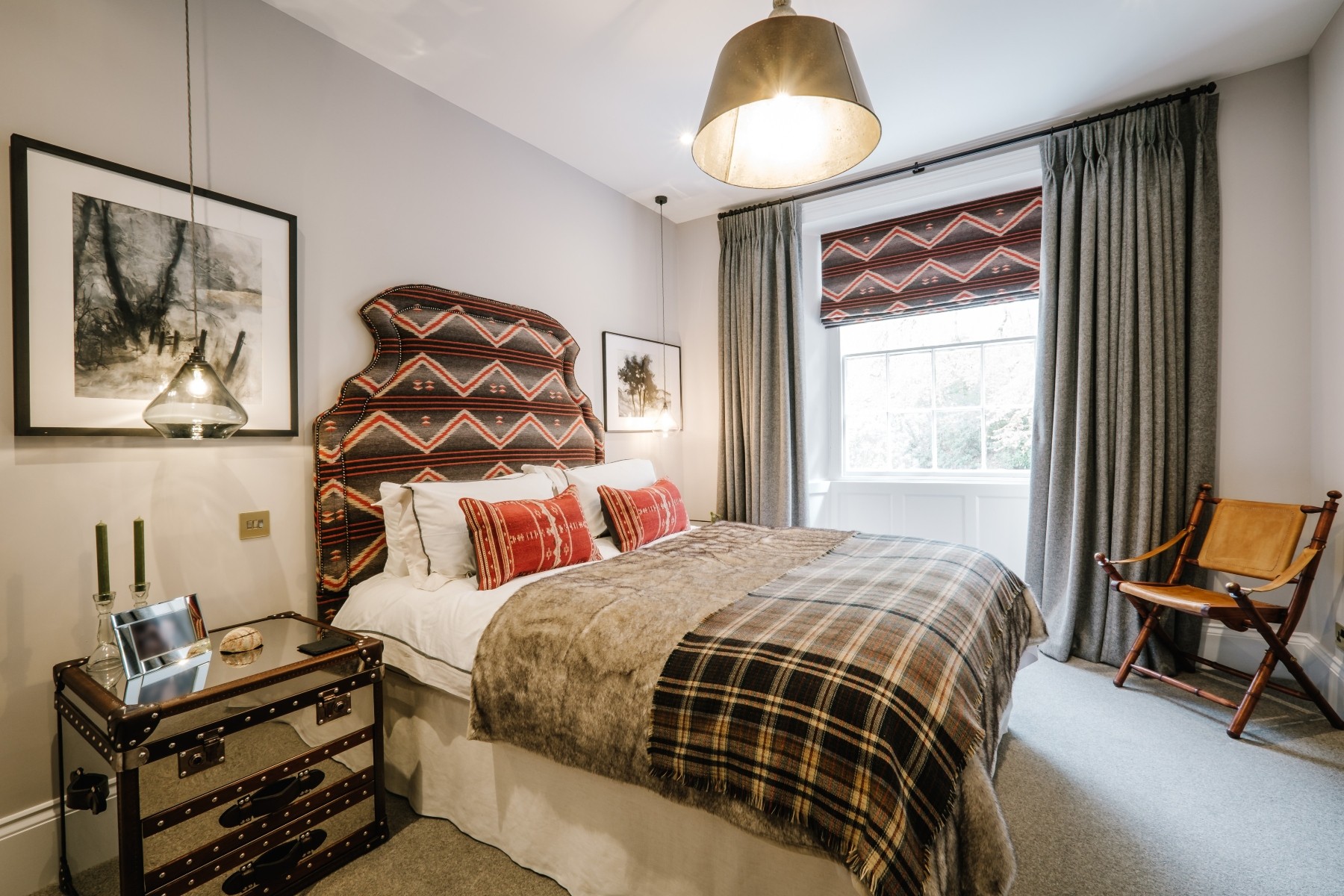 Bedroom with an earthy inspired brown, white and red immersive theme, double bed with headboard, pendant light and full height curtains