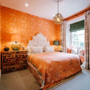 Bedroom with a Moroccan orange coloured theme, view of the double bed, curtains and window