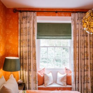 Bedroom with a Moroccan orange coloured theme, view of curtains and window seat