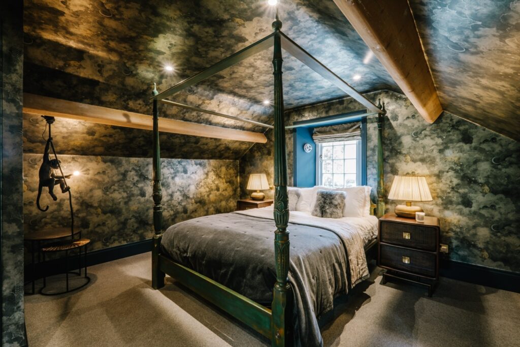 Attic bedroom conversion with a stars and skies theme and fun monkey lights and four poster bed