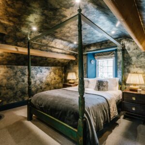 Attic bedroom conversion with a stars and skies theme and fun monkey lights and four poster bed