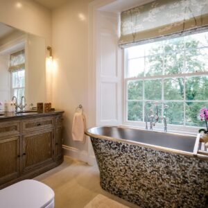 Master ensuite with a mother of pearl freestanding bath, double sink unit and a view of outside