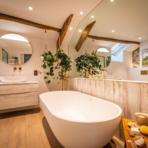 Biophilic designed ensuite bathroom with live hanging plants in oak bent baskets, white bath and large wall mirror