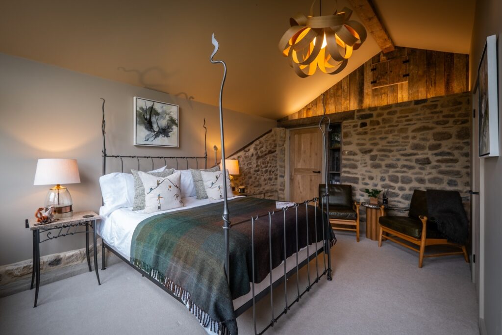 Bedroom with a double bed side on, an exposed stone wall with led lighting