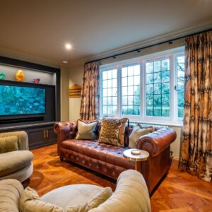 Luxury games room bar area with a chesterfield sofa, media wall and open curtains