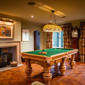 Luxury games room with bespoke Oak pool table, stone fireplace with a tiger artwork wall mounted above