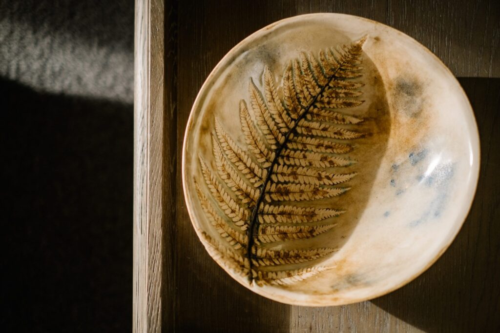 Close up view of an artisan ceramic bowl infused with a fern leaf
